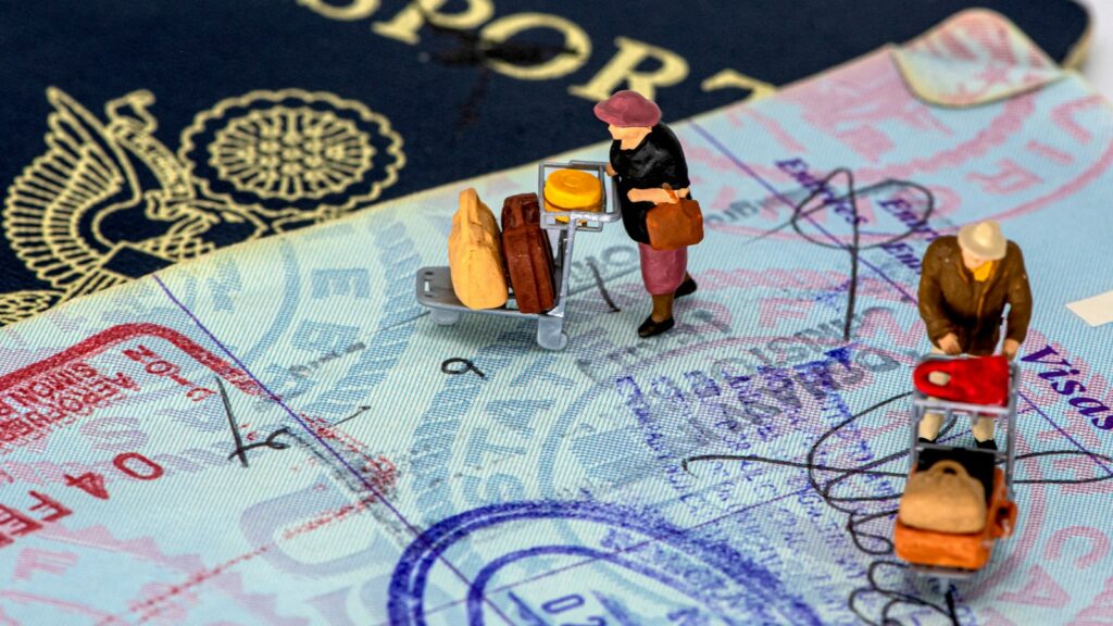 Miniaturas de viajantes com malas sobre página de passaporte carimbada