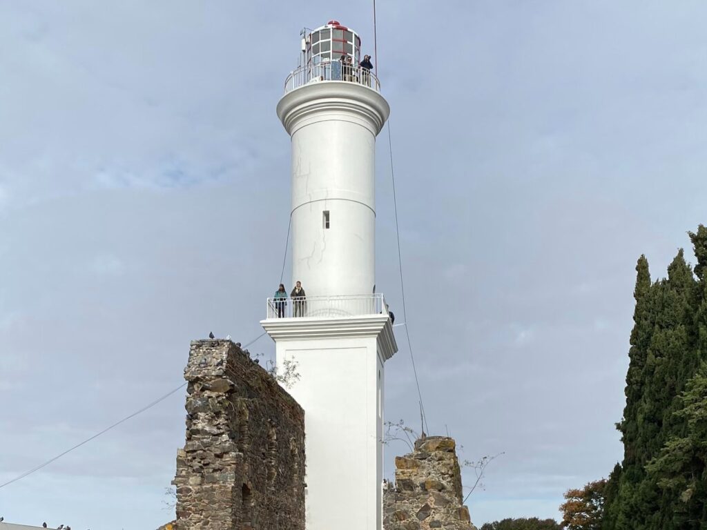 O farol branco de Colônia do Sacramento erguido entre as ruínas de pedra do Convento de São Francisco