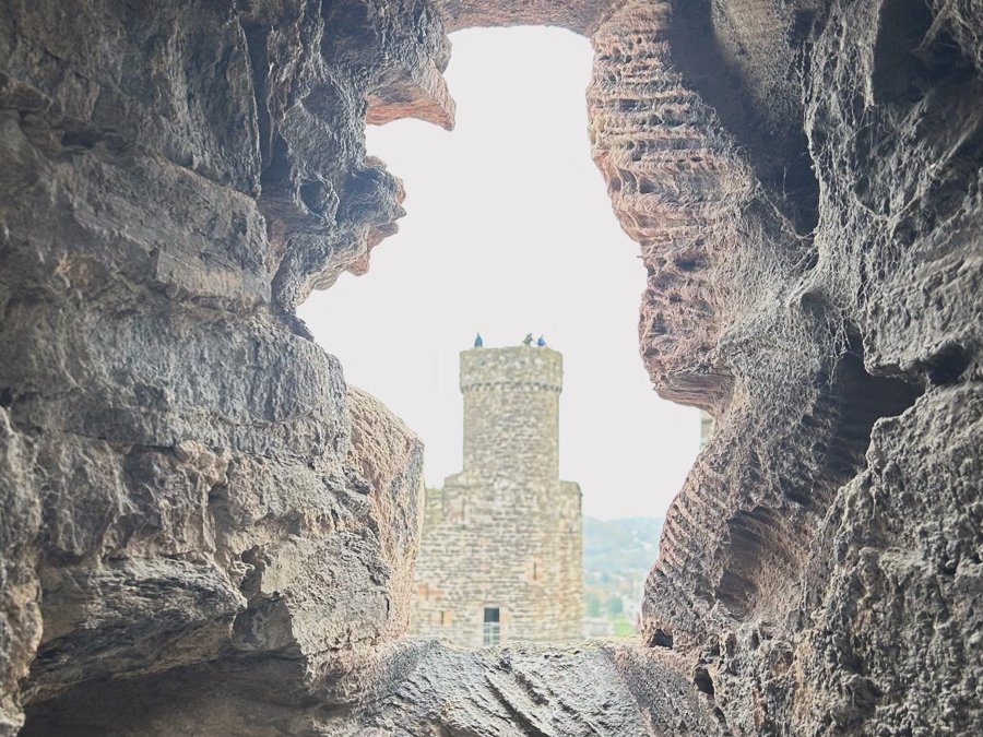 Uma torre do Castelo de Conwy vista através de uma abertura na pedra