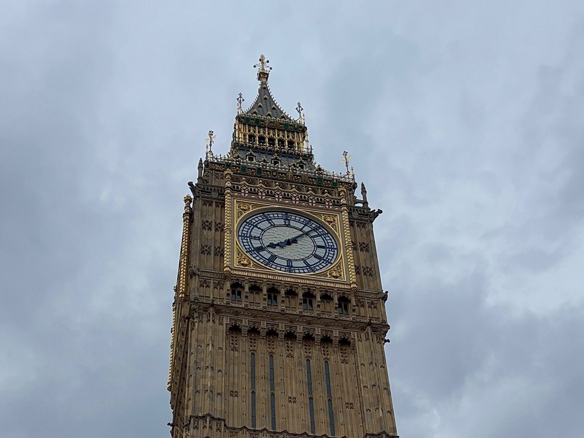 Big Ben visto de baixo, com o relógio dourado e céu nublado de Londres