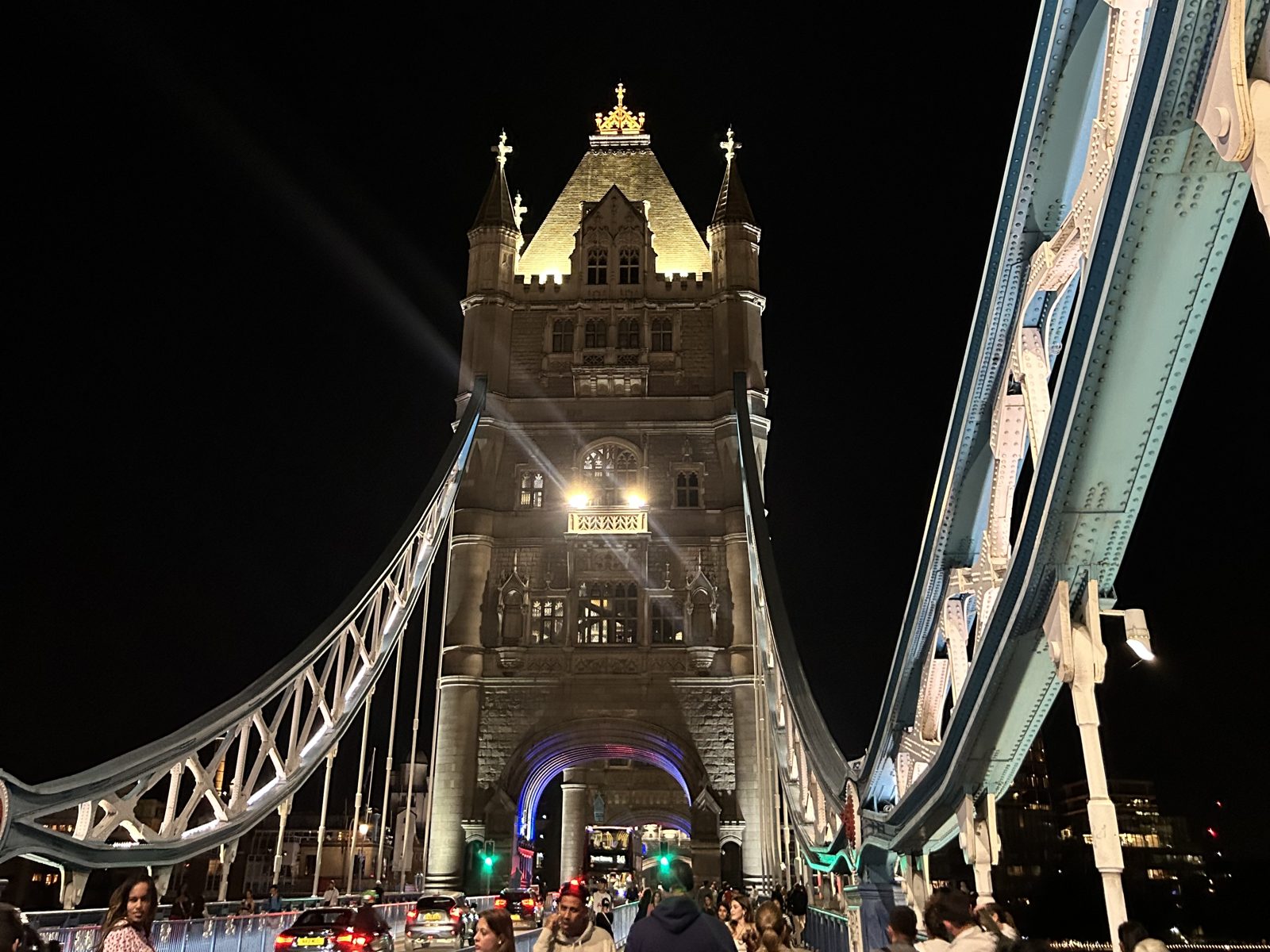 Tower Bridge iluminada à noite, vista de cima da ponte com pedestres atravessando