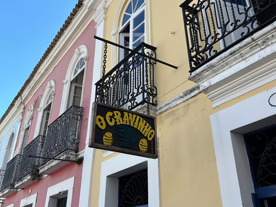 Fachada amarela do bar O Cravinho, com placa de madeira e sacadas de ferro no Pelourinho